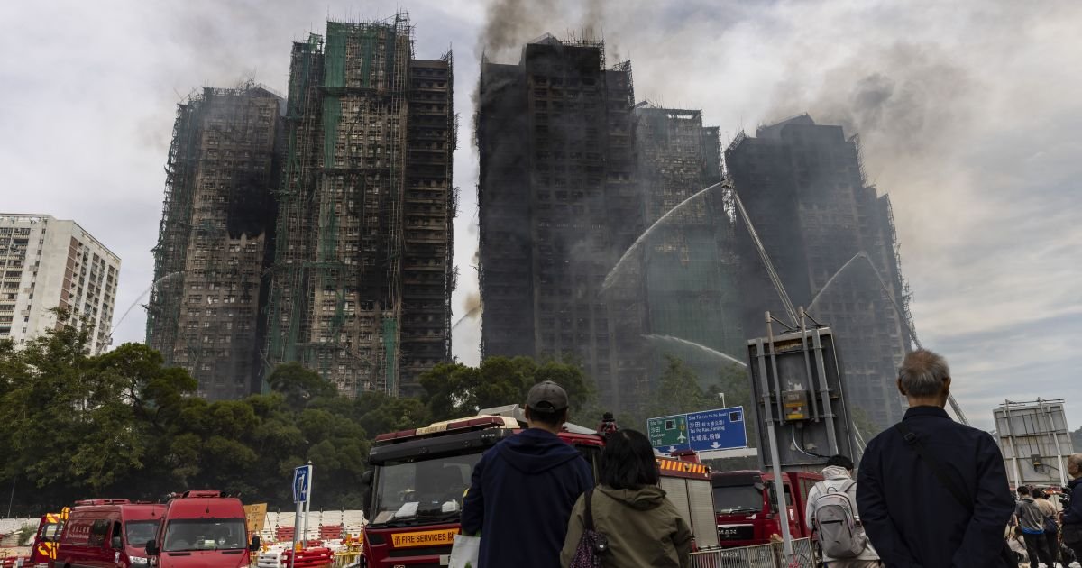 Pessoas observam prédios residenciais atingidos por incêndio em Hong Kong  • Isaac Lawrence/...